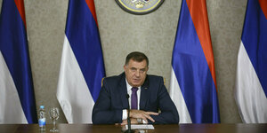 Milorad Dodik sitzt vor Flaggen von Bosnien-Herzegowina