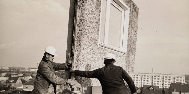 Bauarbeiter montieren eine Fassadenplatte