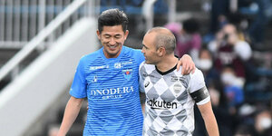 Kazuyoshi Miura und Andres Iniesta gehen Arm in Arm vom Platz
