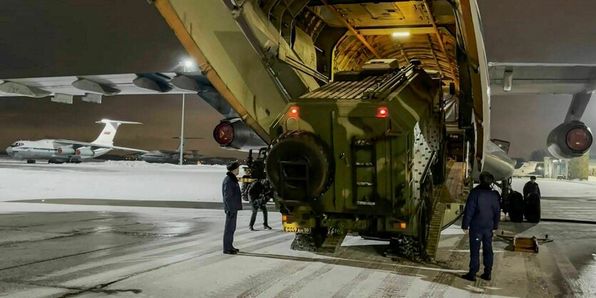 Ein Videostill zeigt ein Militärflugzeug mit einem Panzer, der von Soldaten hineingewinkt wird.