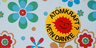 Ein "Atomkraft Bein Danke" Aufkleber liegt auf einer Prilblumen-Decke