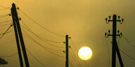Strommasten stehen vor der untergehenden Sonne
