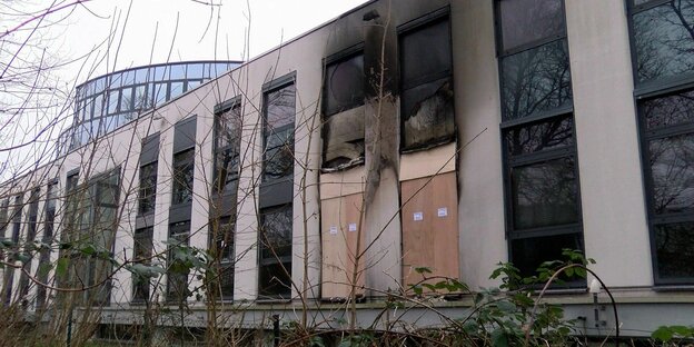 Das OHB-Gebäude in Bremen nach dem Brandanschlag; zwei der haushohen Fenster sind zerstört und teilweise durch Spanplatten ersetzt. Die Rußspuren reichen bis zum Dach