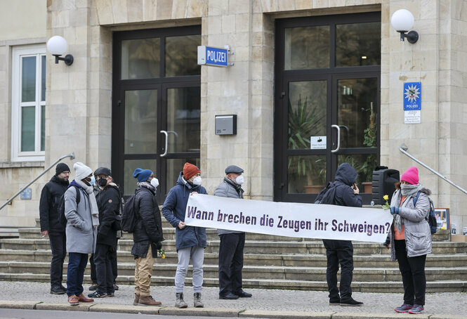 Menschen halten ein Transparent mit der Aufschrift "Wann brechen die Zeugen ihr Schweigen"