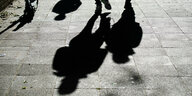 Menschen werfen lange Schatten auf die Straße