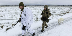 Zwei bewaffnete und uniformierte Personen im Schnee