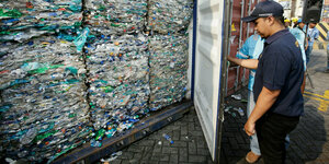 Ein indonesischer Zollbeamter vor einem Container mit Plastikmüll