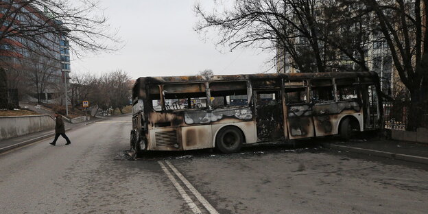Ein ausgebrannter Bus steht quer auf einer Straße in der kasachischen Hauptstadt Almaty
