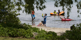 Kinder spielen im Wasser mit Luftmatrazen