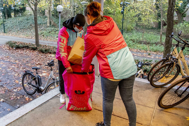 Eine Frau packt eine Tüte mit Waren in den Rucksack einer anderen Frau