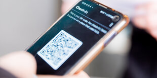 Ein Mensch hält ein Handy mit einem QR-Code