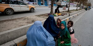Zwei Frauen und drei Mädchen sitzen bettelnd am Strassenrand