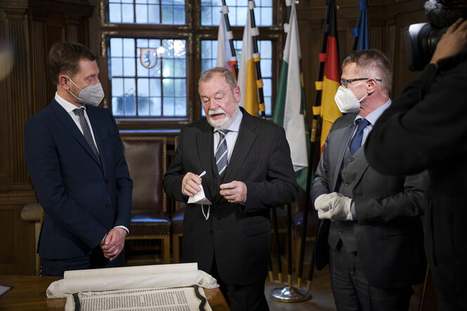 Ministerpräsident Michael Kretschmer Uwe Mader, der Archivar Siegfried Hoche stehen vor der Tora-Rolle