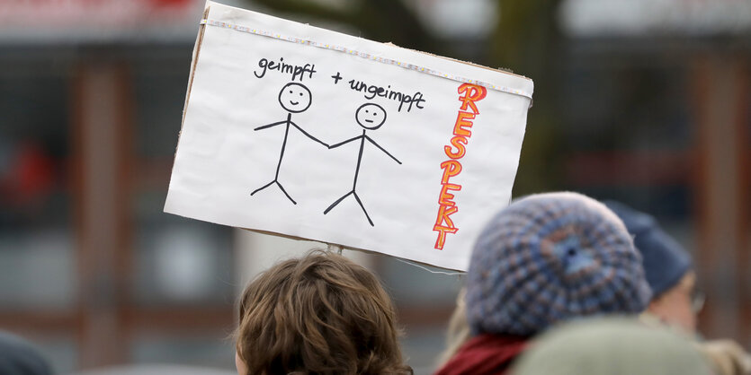 Frauen halten ein Schild mit geimpften und ungeimpften Strichmännchen hoch mit der Aufschrift "Respekt"