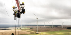 Industriekletterer prüfen in großer Höhe das Rotorblatt einer Windkraftanlage