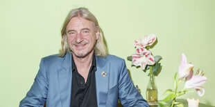 Frank Otto sitzt in einem Café neben einer Vase mit Blumen.