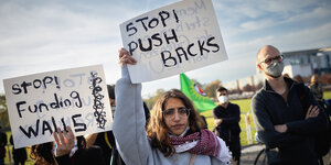 menschen protestieren, eine Frau hält ein Plakat mit der Aufschrift " Stop Pushbacks" hoch