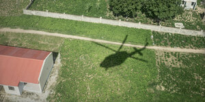 Die Aufnahme zeigt den Schatten eines Hubschraubers und ein zerstörtes Haus im Norden Nigerias