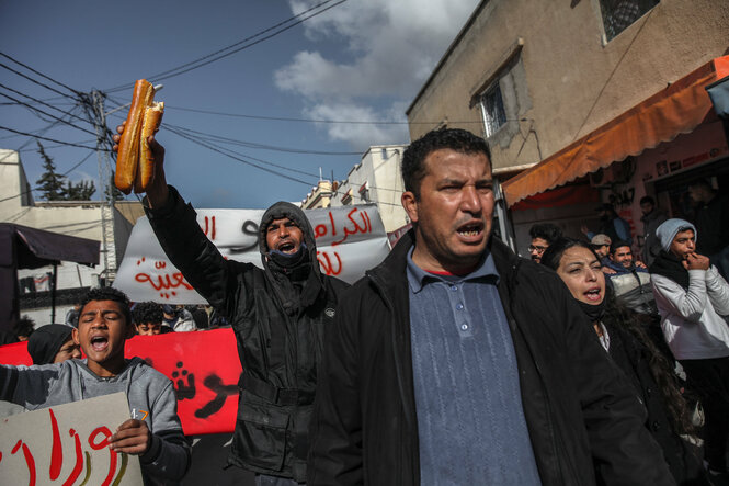 Ein Demonstrant in Tunis hält ein zerbrochenes Baguette in die Höhe