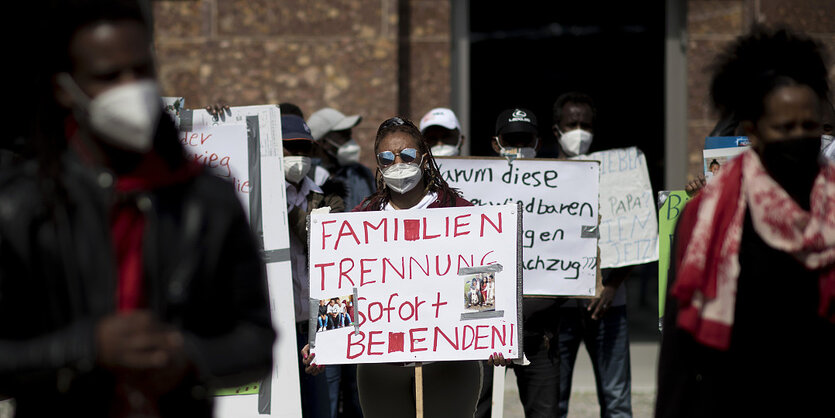 "Familientrennung sofort beenden" steht rot auf dem Transparent zwischen einer Menschengruppe