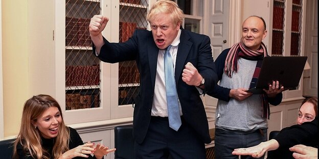 Boris Johns (in der Bildmitte) und Dominic Cummings und Carrie Symonds. Boris Johnson macht eine Grimasse und reckt seine Fäuste