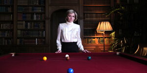 Kristen Stewart steht in einer hochgeschlossenen weißen Bluse als Lady Diana hinter einem Billiardtisch