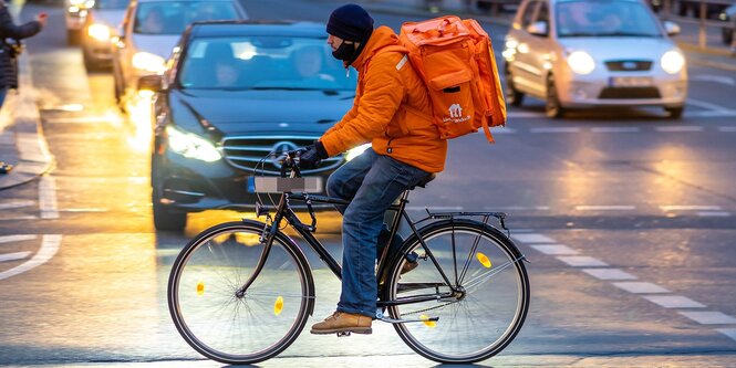 Ein Liferando-Fahrer auf regennasser Straße