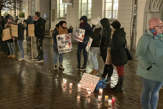 Frauen mit Protestplakaten stehen an der Straße