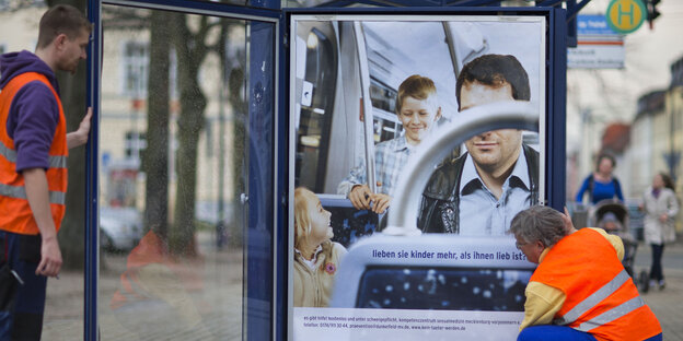 Mitarbeiter einer Werbefirma hängen am 15.04.2013 in Schwerin (Mecklenburg-Vorpommern) Plakate einer Informationsaktion zum Pädophilie-Präventionsprojekt in Mecklenburg-Vorpommern auf.