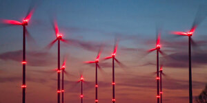 Rot beleuchtete Windräder in der Dämmerung