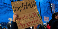 Eine Teilnehmerin einer Demonstration gegen Corona-Einschränkungen zieht in durch die Hamburger Innenstadt und hält ein Schild mit der Aufschrift „Impfplicht? Heute wir, morgen ihr!“ hoch.