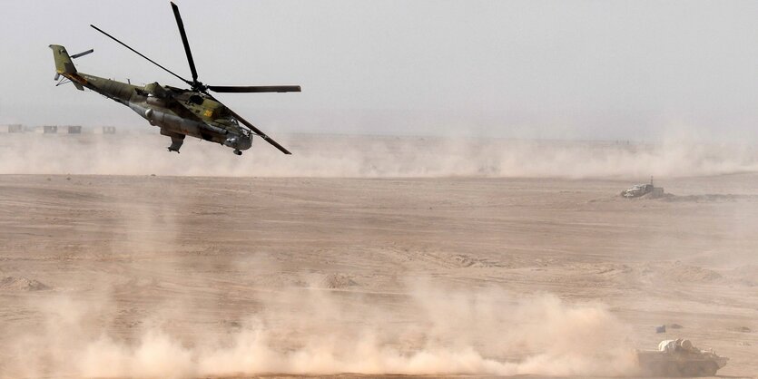 Helicopter fliegt über Staub, der von Panzern hochgewirbelt wird