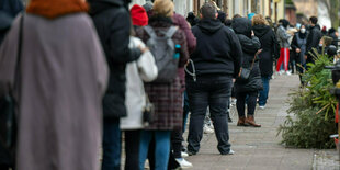 Eine lange Menschenschlange auf dem Gehweg