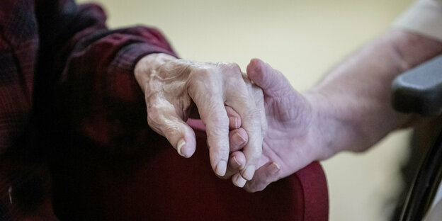 Pflegekraft hält die Hand einer älteren Person