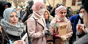 Eine Gruppe von Frauen steht mit Fotos von Folteropfern vor dem Gericht