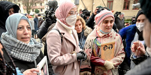 Eine Gruppe von Frauen steht mit Fotos von Folteropfern vor dem Gericht