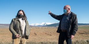 Montse García und Armando Pérez vor einem Feld, auf dem die größte Rinderfarm Europas entstehen soll