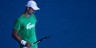 Novak Đoković schaut auf dem Tennisplatz nachdenklich auf seinen Schläger