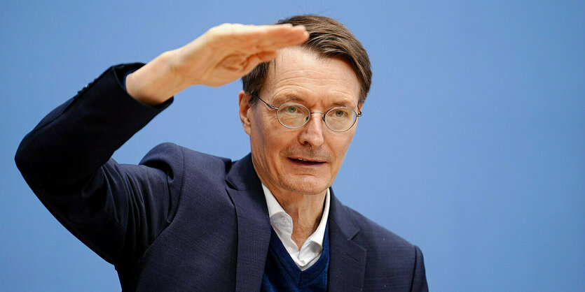 Karl Lauterbach in der bundespressekonferenz. Er macht ein zeichen mit seiner Hand