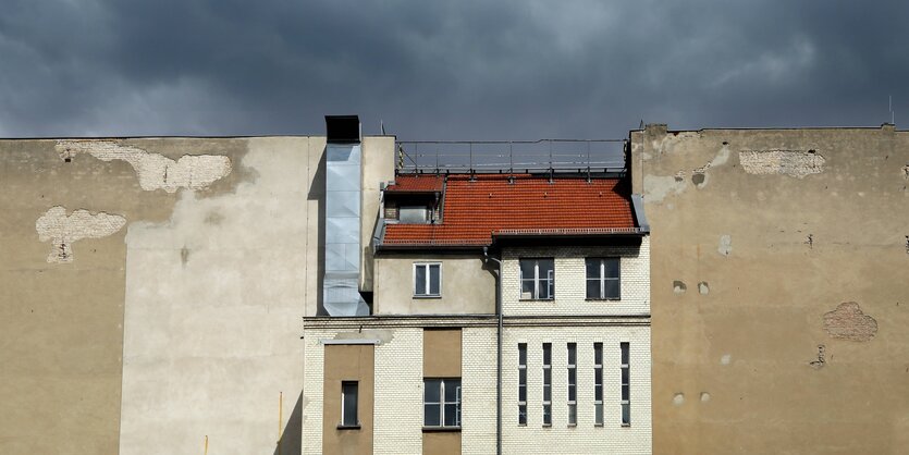 eine Hausfassade mit Fenstern und dach auf einer nackten Häuserwand