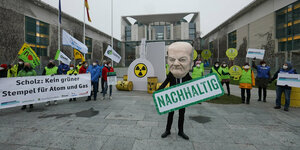 ein als Kanzler Scholz verkleideter Aktivist vor dem Bundeskanzleramt hält ein Transparent mit der Aufschrift "Nachhaltig" in den Händen