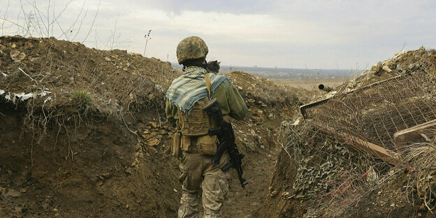 Ein ukrainischer Soldat mit einer Katze in einem Graben