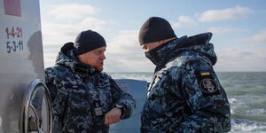 Zwei Männer mit Mützen und in Uniform auf einem Schiff