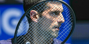 Der Kopf von Djokovic hinter den Saiten eines Tennisschlägers
