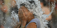 Ein Kind hält seinen Kopf unter einen Wasserstrahl