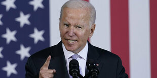 US-Präsident Biden mit angestrengtem Blick und erhobenem Zeigefinger vor der US-Flagge