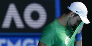 Der serbische Tennisprofi Novakk Djokovic wischt sich mit seinem T-Shirt das Gesicht