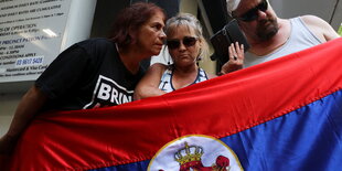 Menschen mit einer Flagge und einem Handy in der Hand