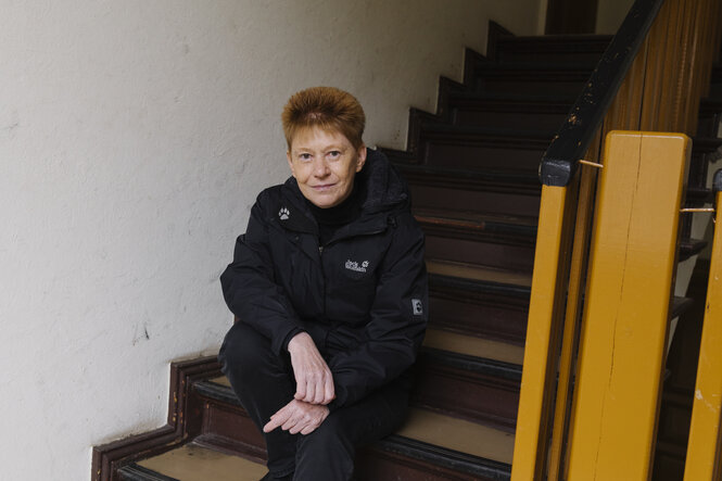 Petra Pau sitzt auf einer Treppe im Hausflur