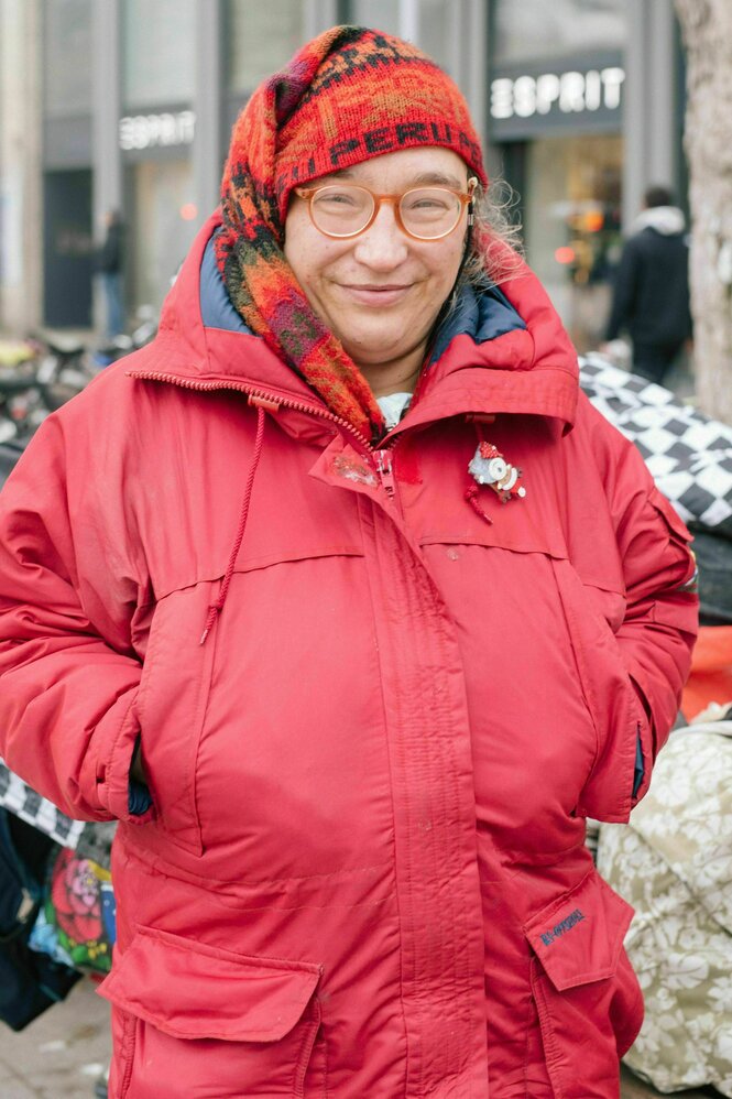 Eine Frau mit roter Mütze und rotem Anorak steckt die Hände in die Tasche